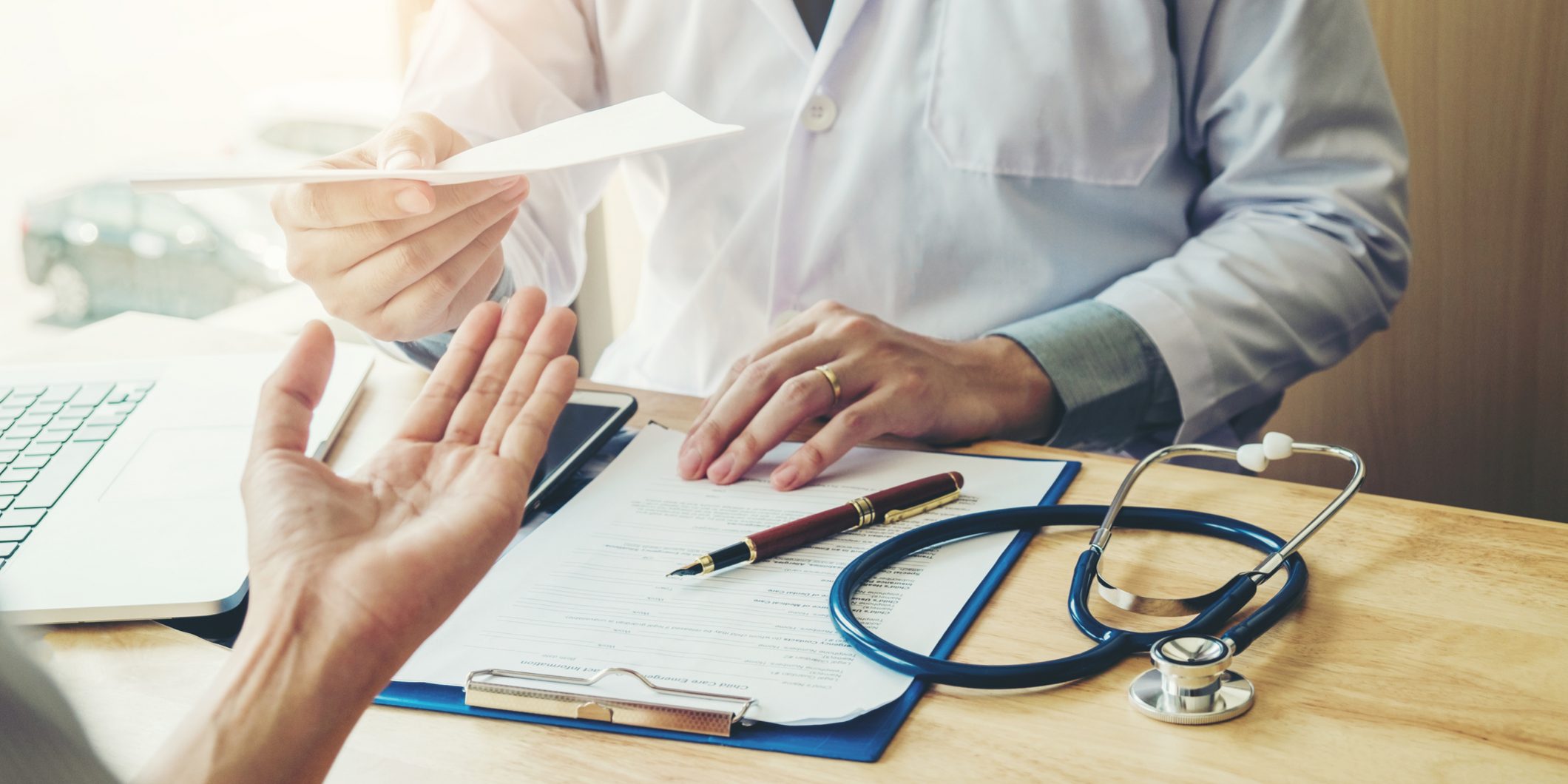 Doctor or physician writing diagnosis and giving a medical prescription to female Patient